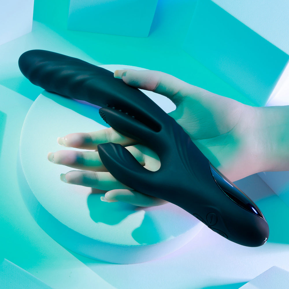 Black silicone vibrator with textured surface held by a hand.