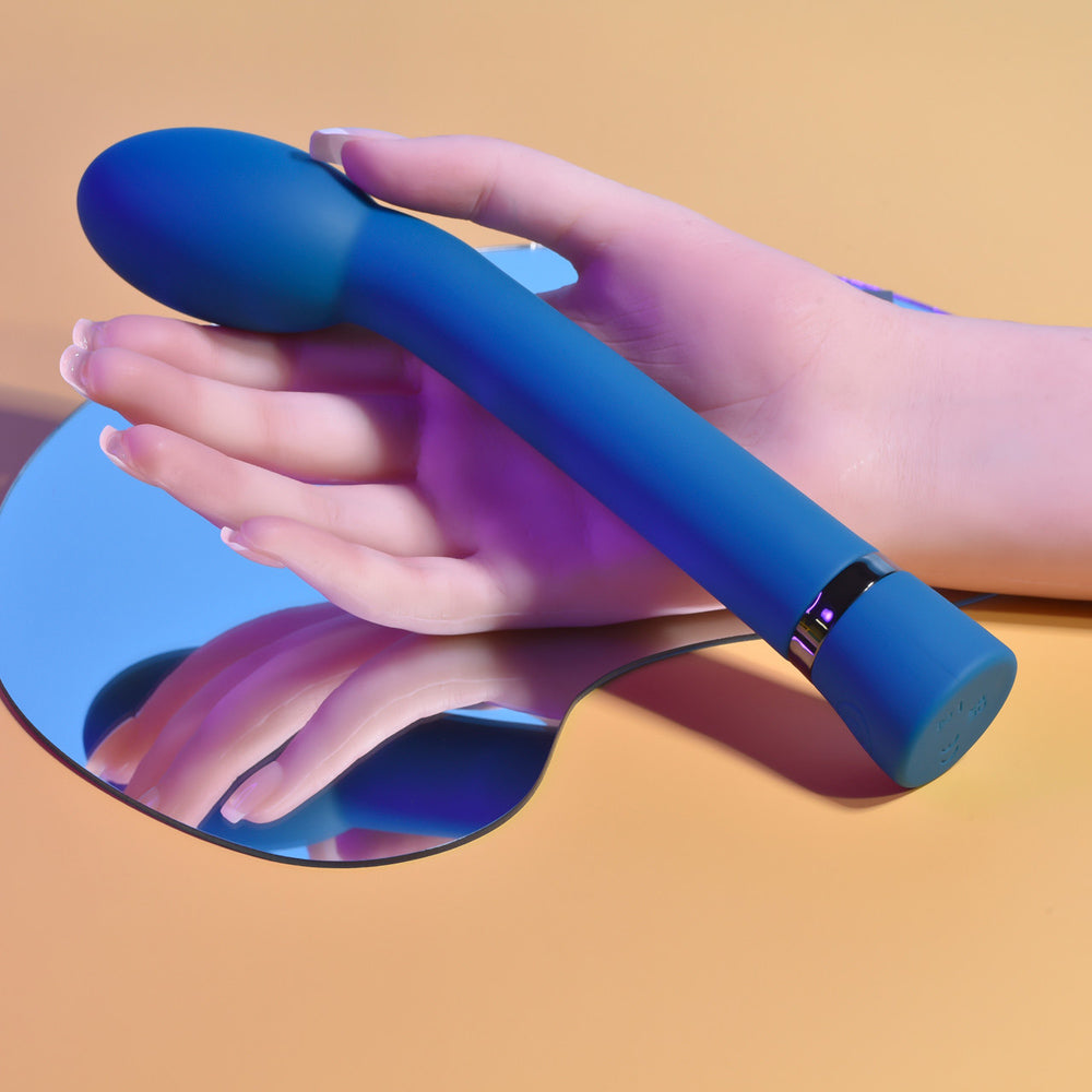 Blue G-spot vibrator held by a hand over a mirror.