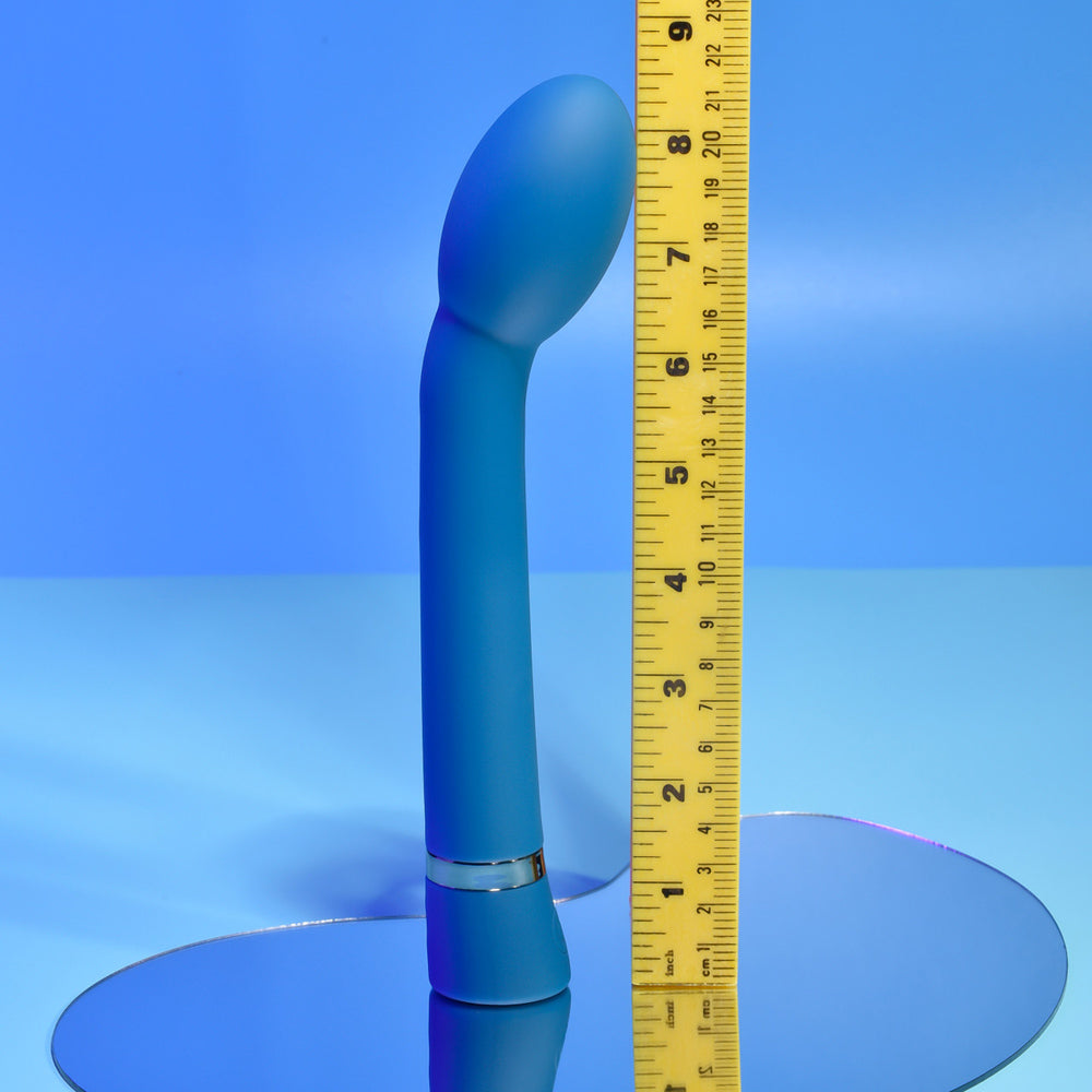 A blue G-spot vibrator with a curved shaft is shown next to a ruler.