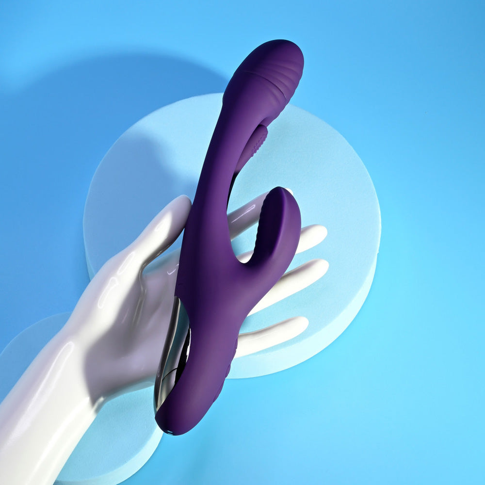 A purple rabbit vibrator with a ribbed head and a silver accent rests on a white mannequin hand.