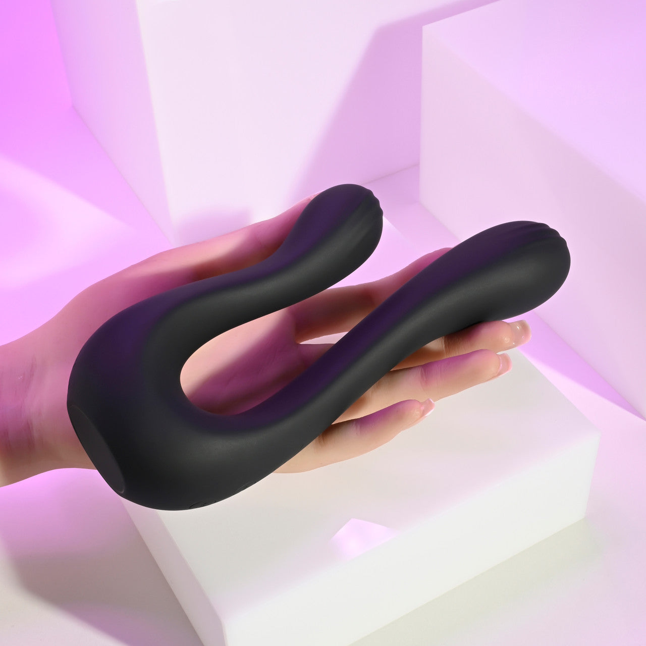 A black dual silicone vibrator held in a hand.