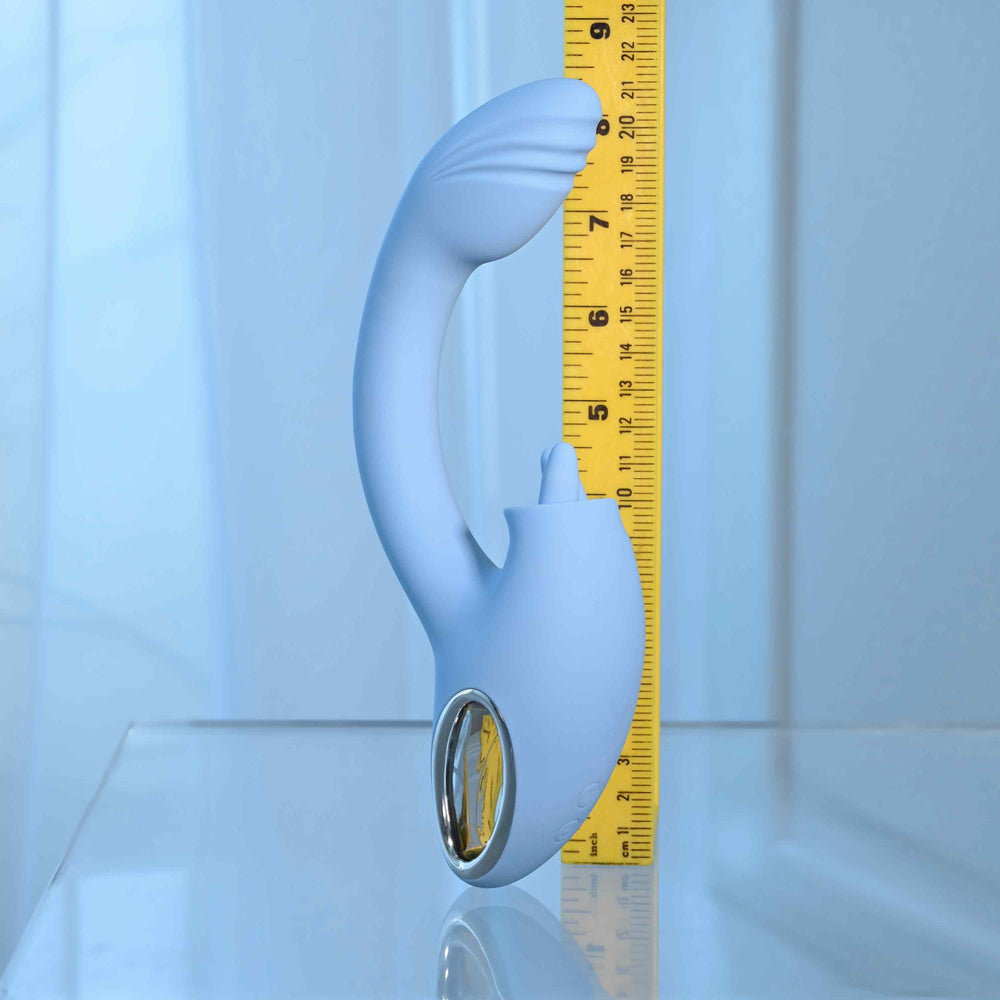 A light blue dual vibrator with a curved shaft and a silver accent, measured against a ruler.