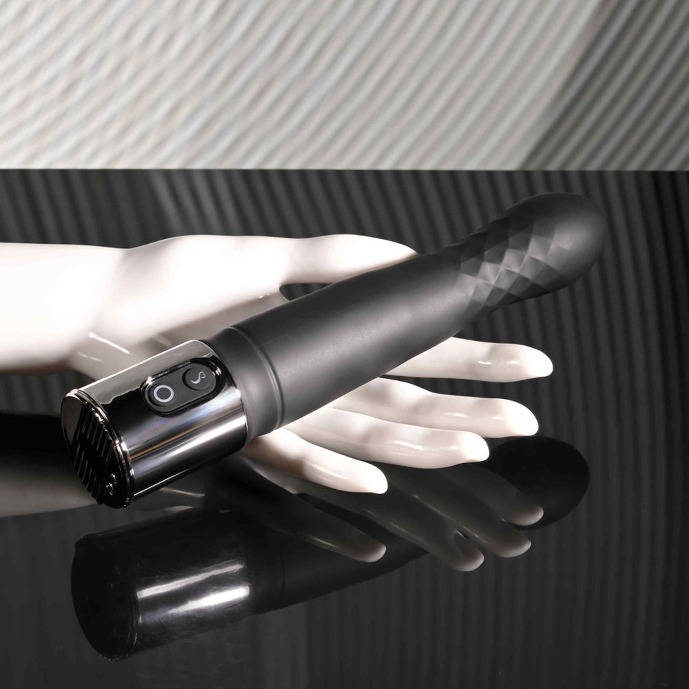 Black silicone vibrator with textured tip and control buttons on a white mannequin hand.