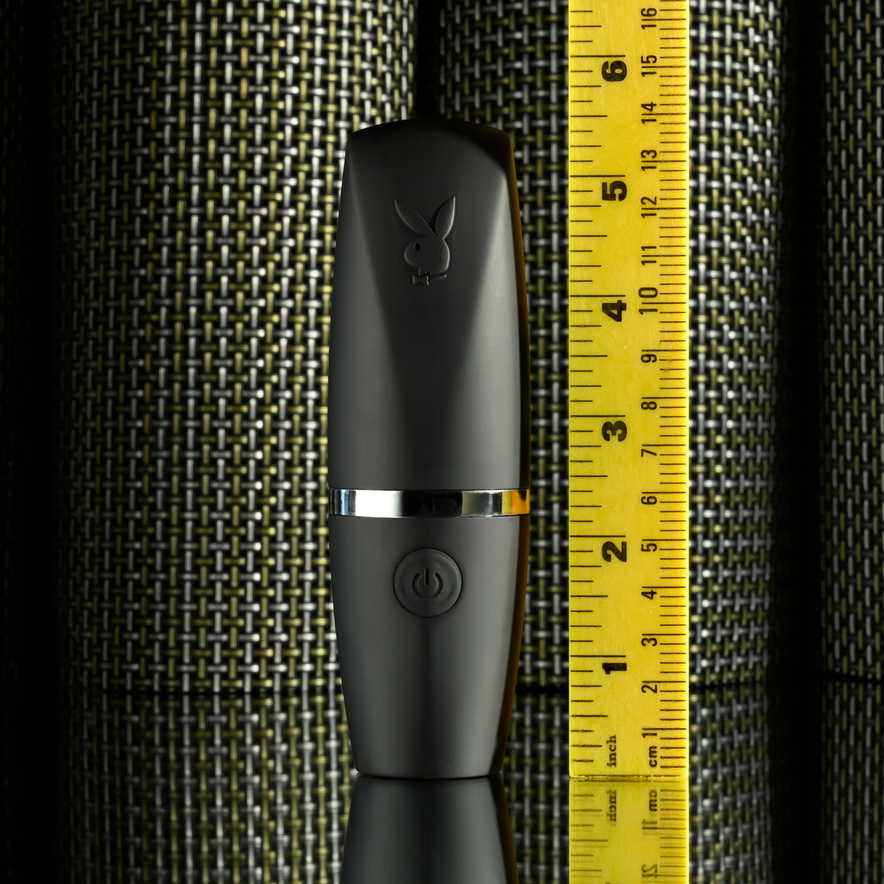 Black Playboy suction vibrator with a power button and silver band, next to a ruler.