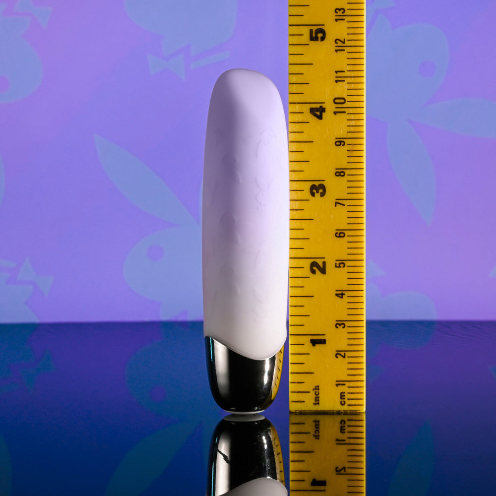 A purple bullet vibrator with a silver base is shown next to a ruler.