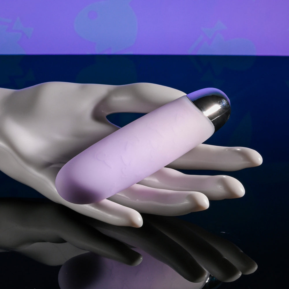 A purple silicone bullet vibrator with a silver tip rests on a white mannequin hand.