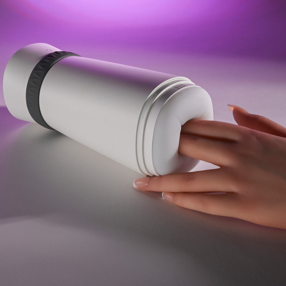 White vibrating stroker with a textured opening and a hand inserting a finger.