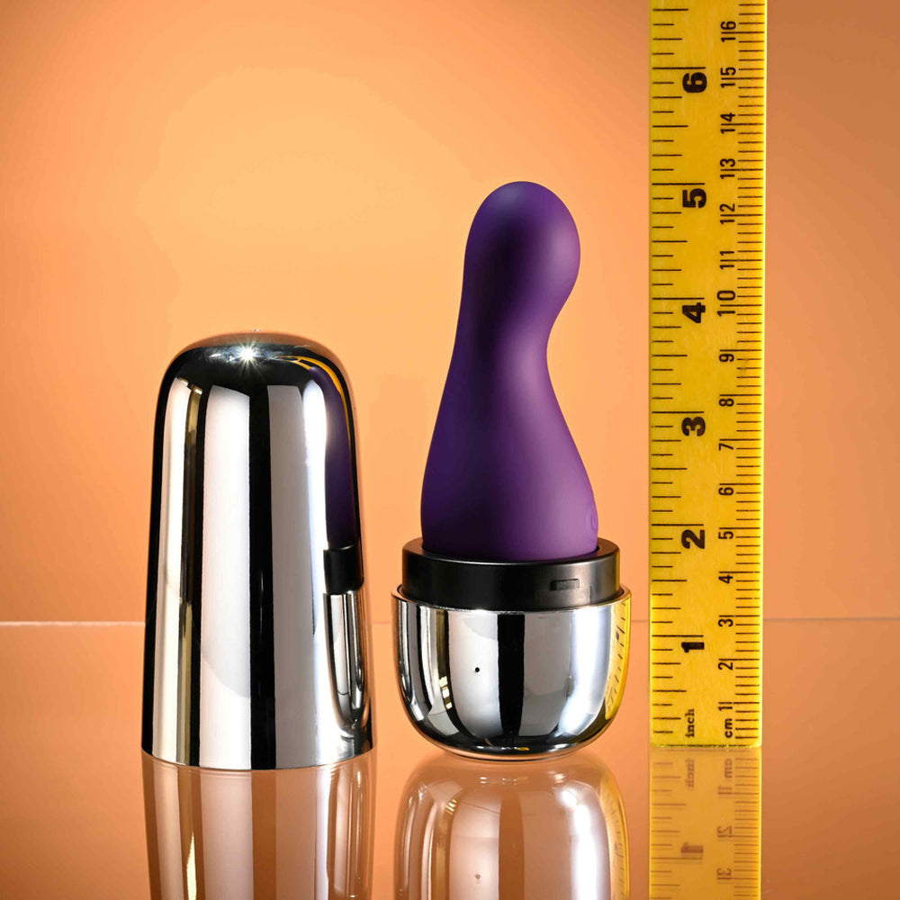 Purple silicone vibrator with a chrome travel case next to a ruler.