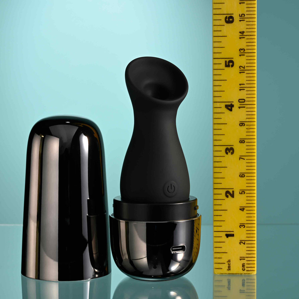 Black clitoral suction toy with a metallic charging case and a ruler for scale.