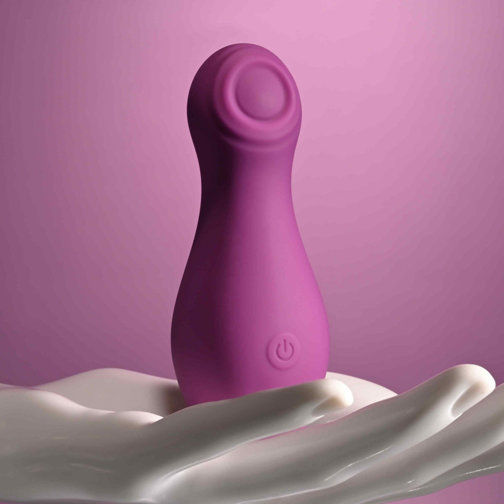 Purple silicone clitoral tapping toy with a power button.