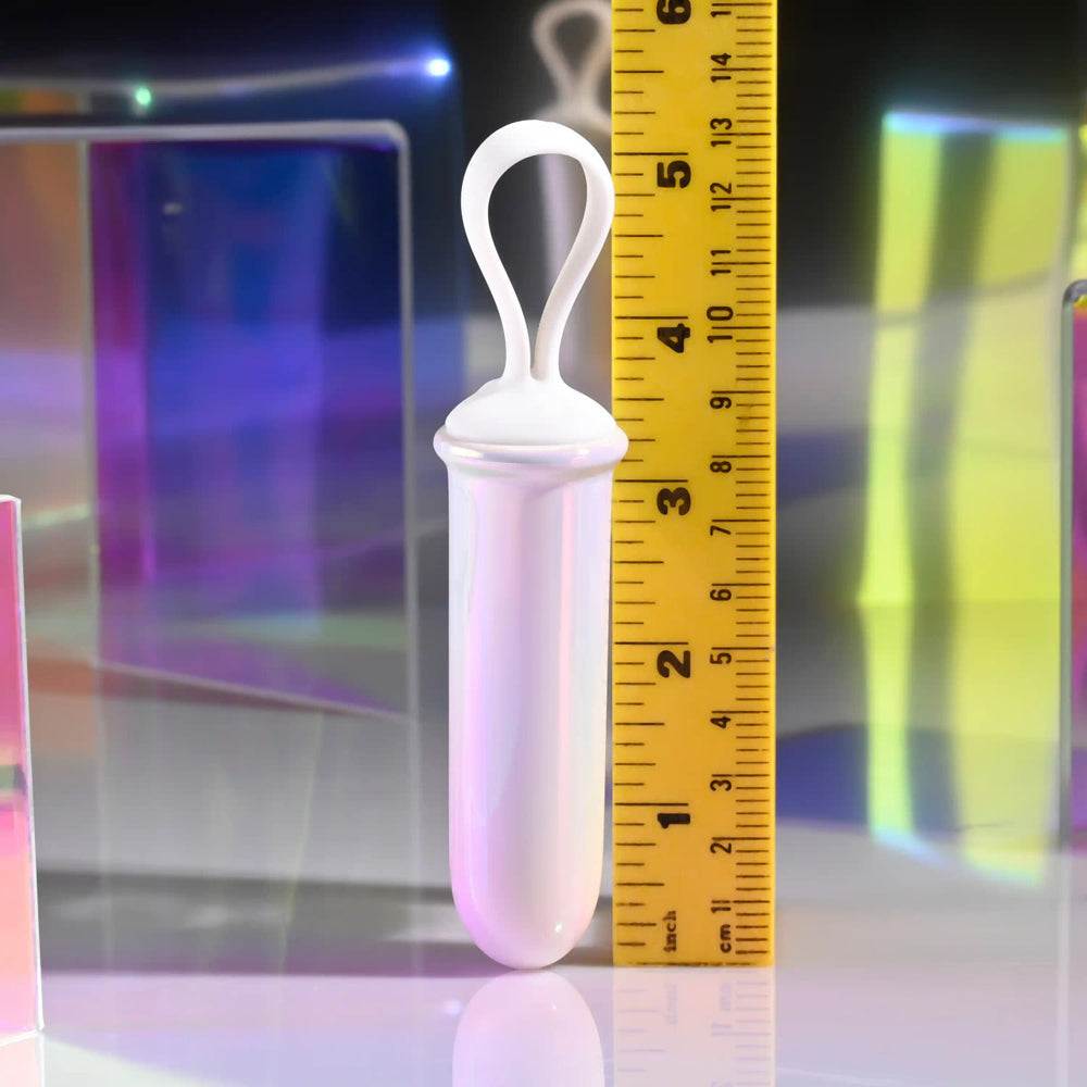 A pearlescent silicone bullet vibrator with a finger loop, next to a ruler.