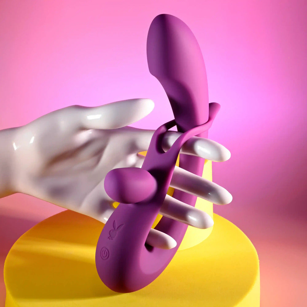 Purple dual silicone vibrator held by a white mannequin hand.