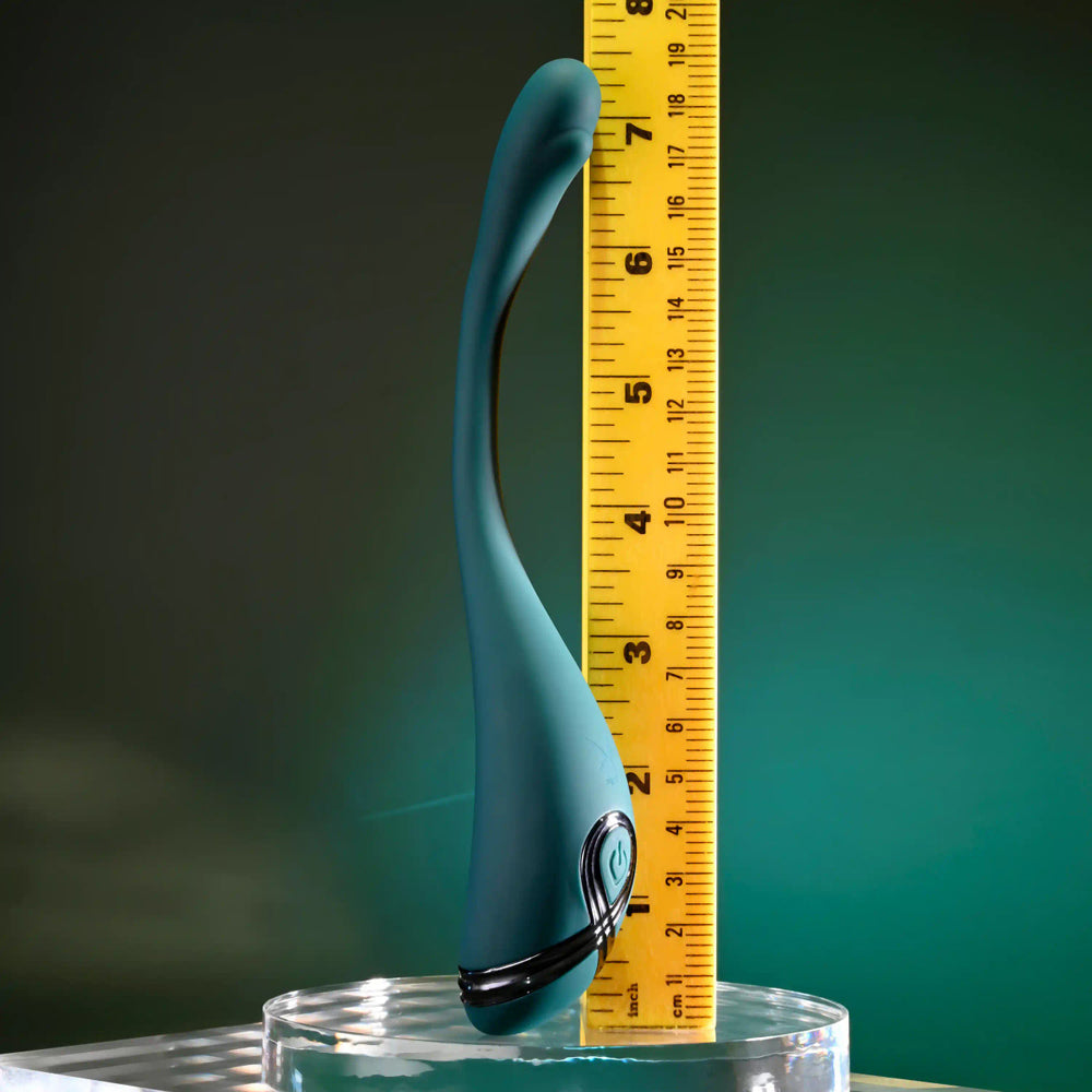 A teal bendable vibrator is shown next to a yellow ruler measuring its length.