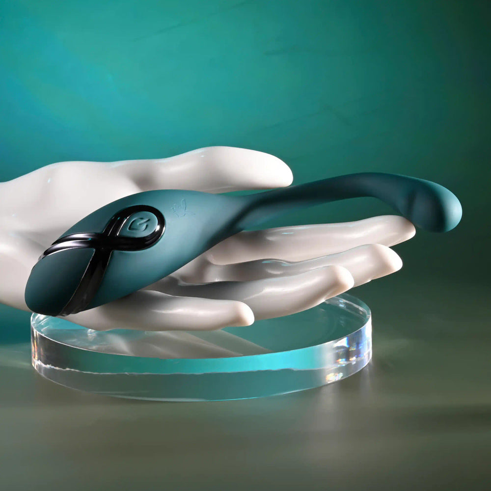 A teal bendable vibrator with a black accent rests on a white mannequin hand.