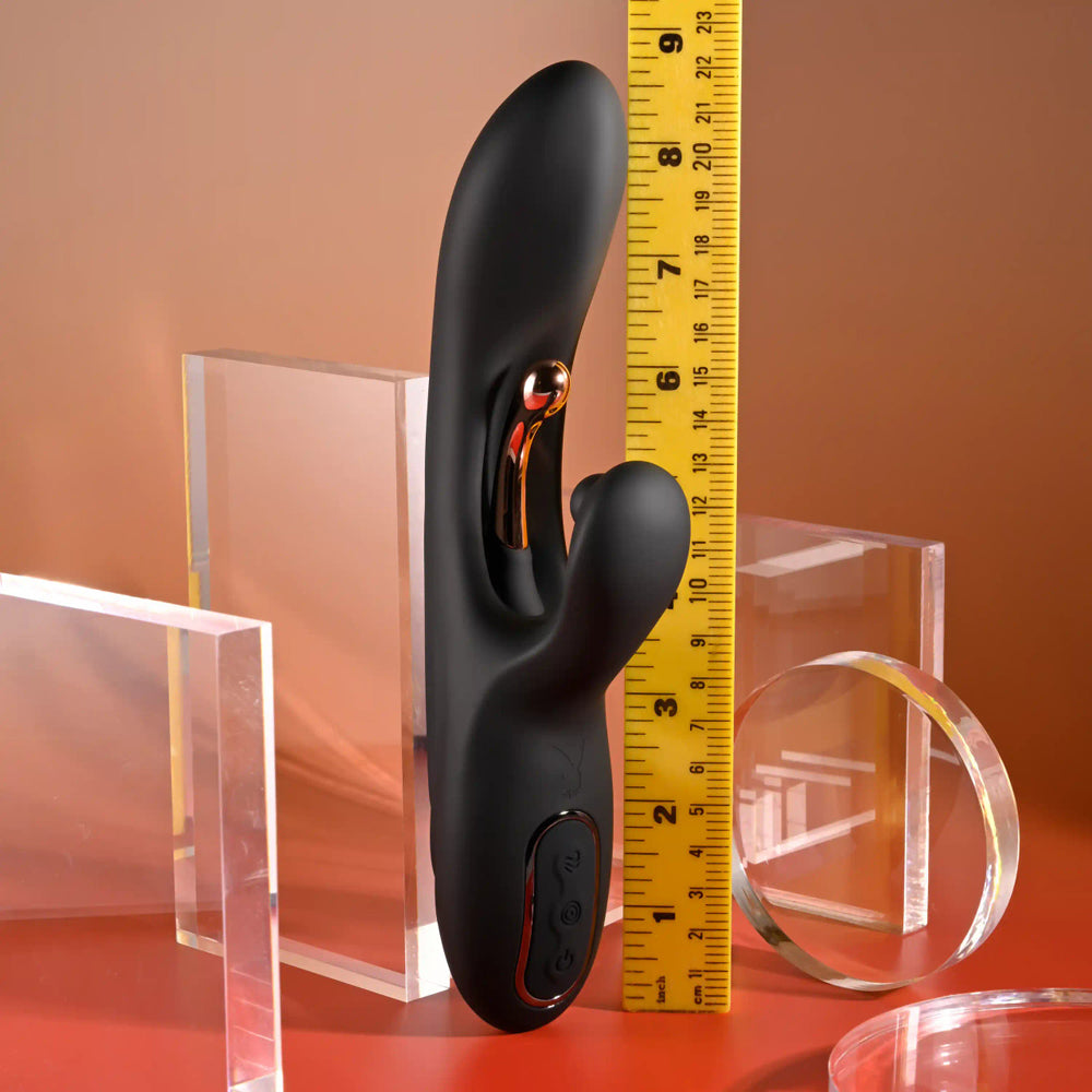 Black silicone G-spot vibrator with rose gold accents and a ruler for scale.