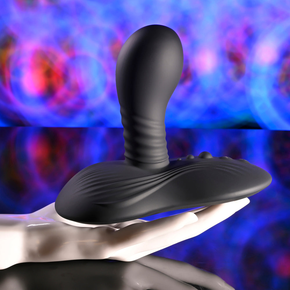 Black rotating vibe with textured shaft and wide base on a white hand.