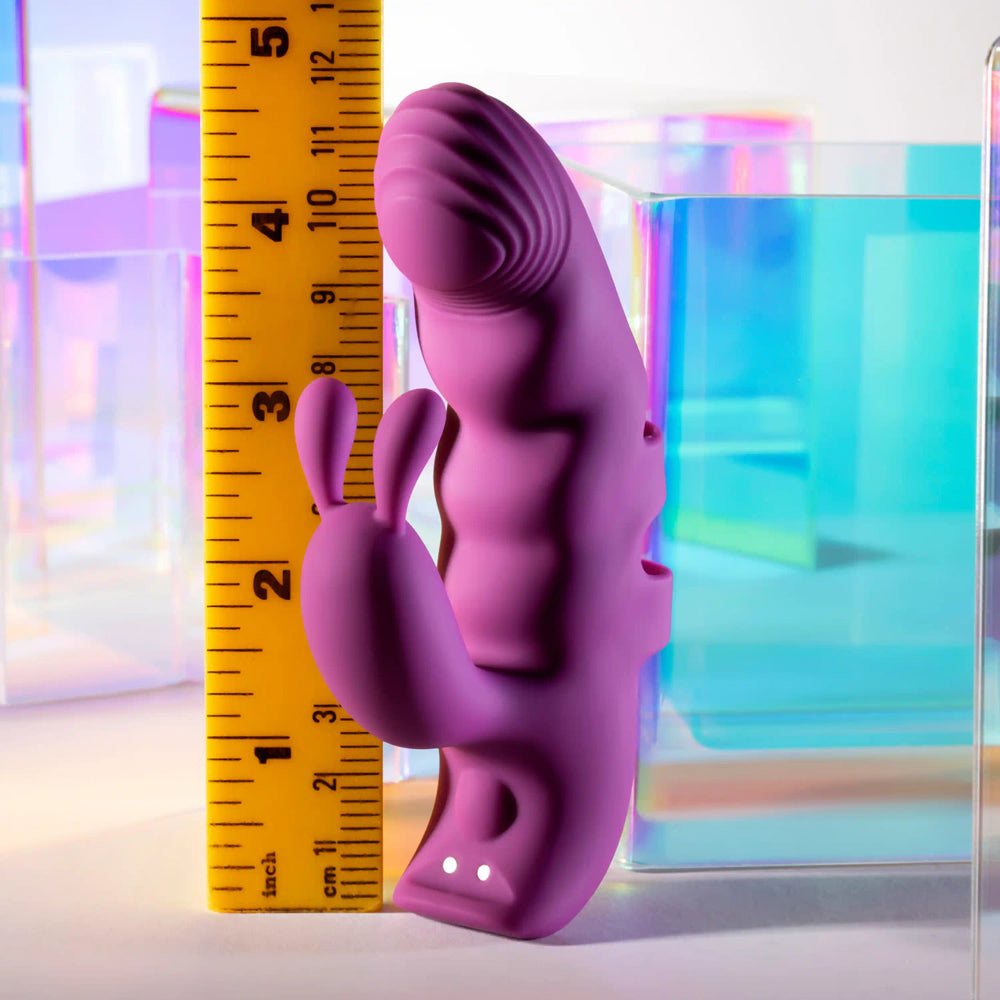 A purple G-spot finger vibrator with bunny ears and a ruler for scale.