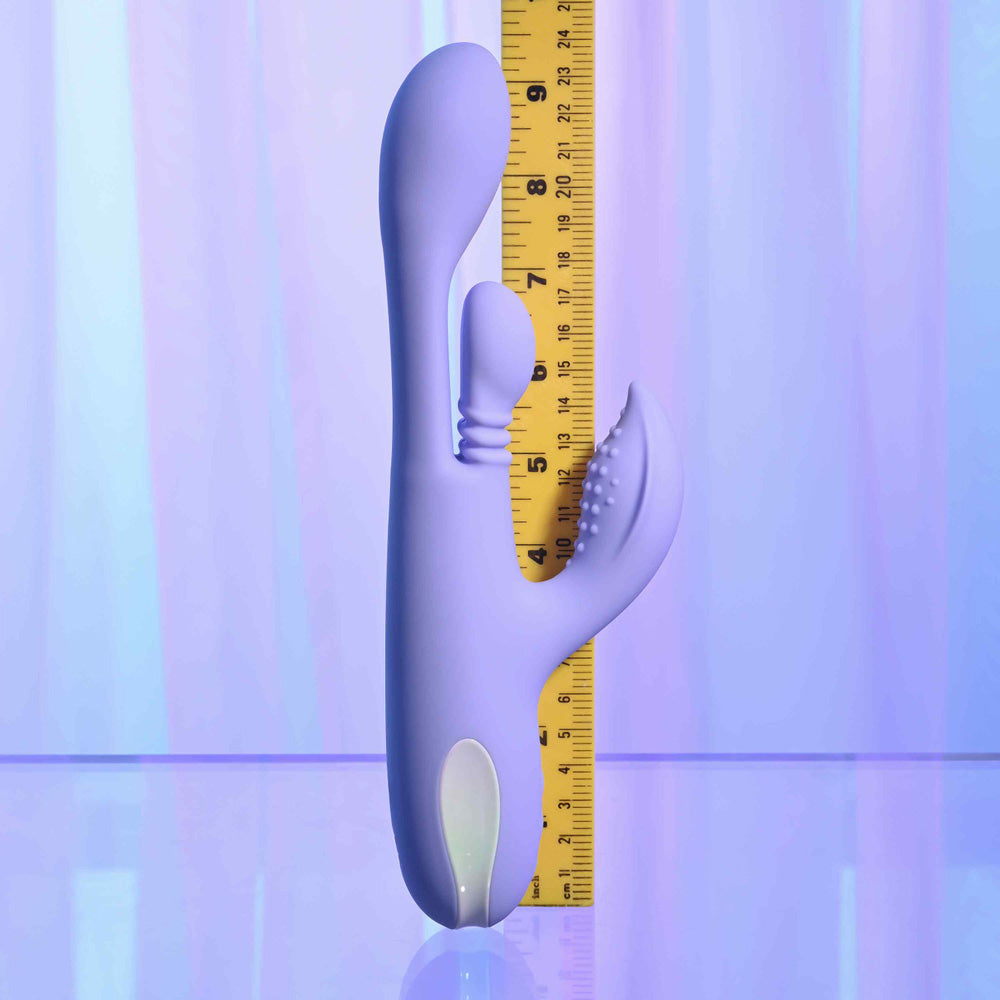 A purple dual thrusting silicone vibrator with a ruler for scale.