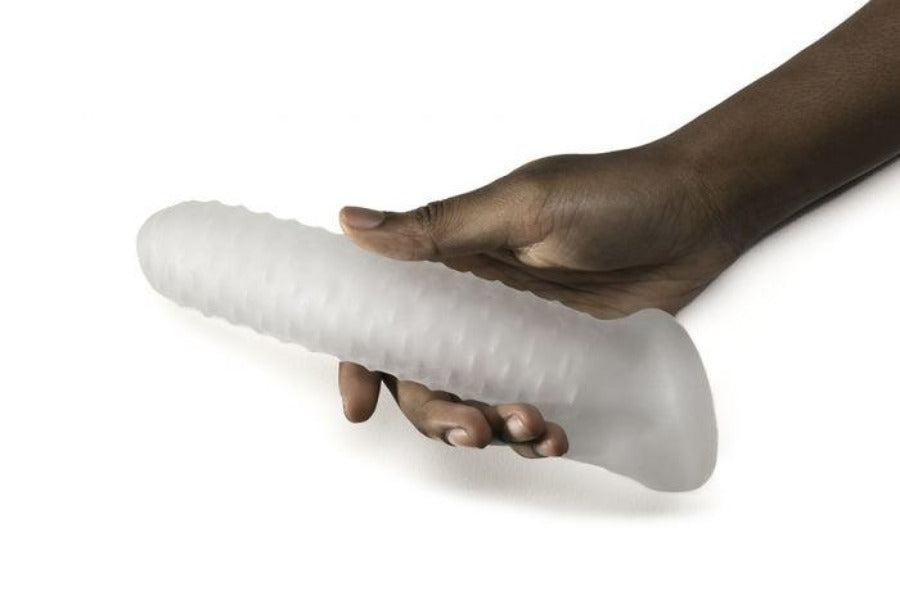 A textured penis sheath extender held by a hand.