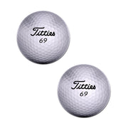 Two white golf balls with "Titties 69" printed on them.