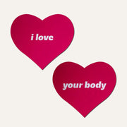 Pink heart nipple pasties with "i love your body" text.