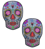 Two glittery sugar skull pasties with colorful floral and heart designs.