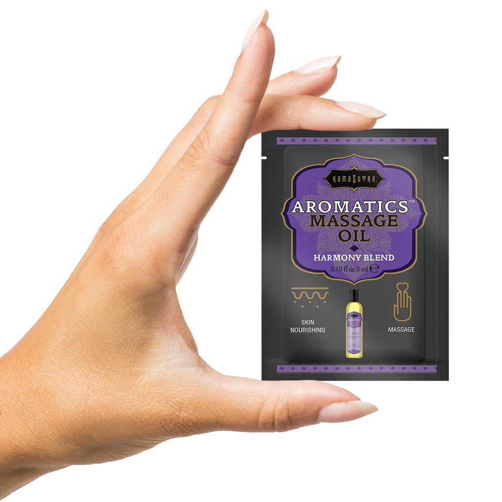 Kama Sutra Aromatics massage oil packet held by a hand.