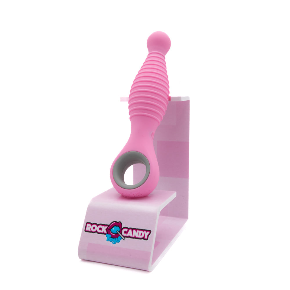 Pink ribbed vibrator with a grey ring on a pink stand with the Rock Candy Toys logo.