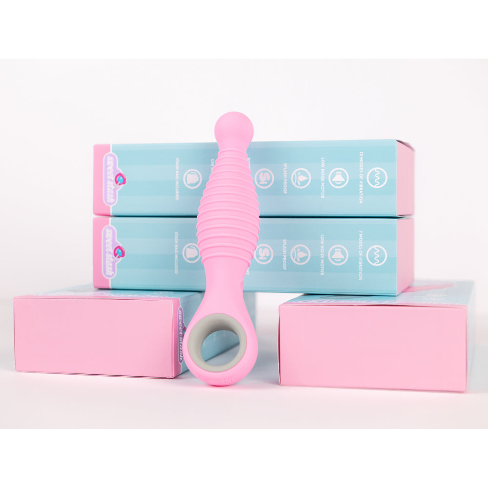 A pink ribbed anal vibrator with a finger loop, displayed with its packaging.