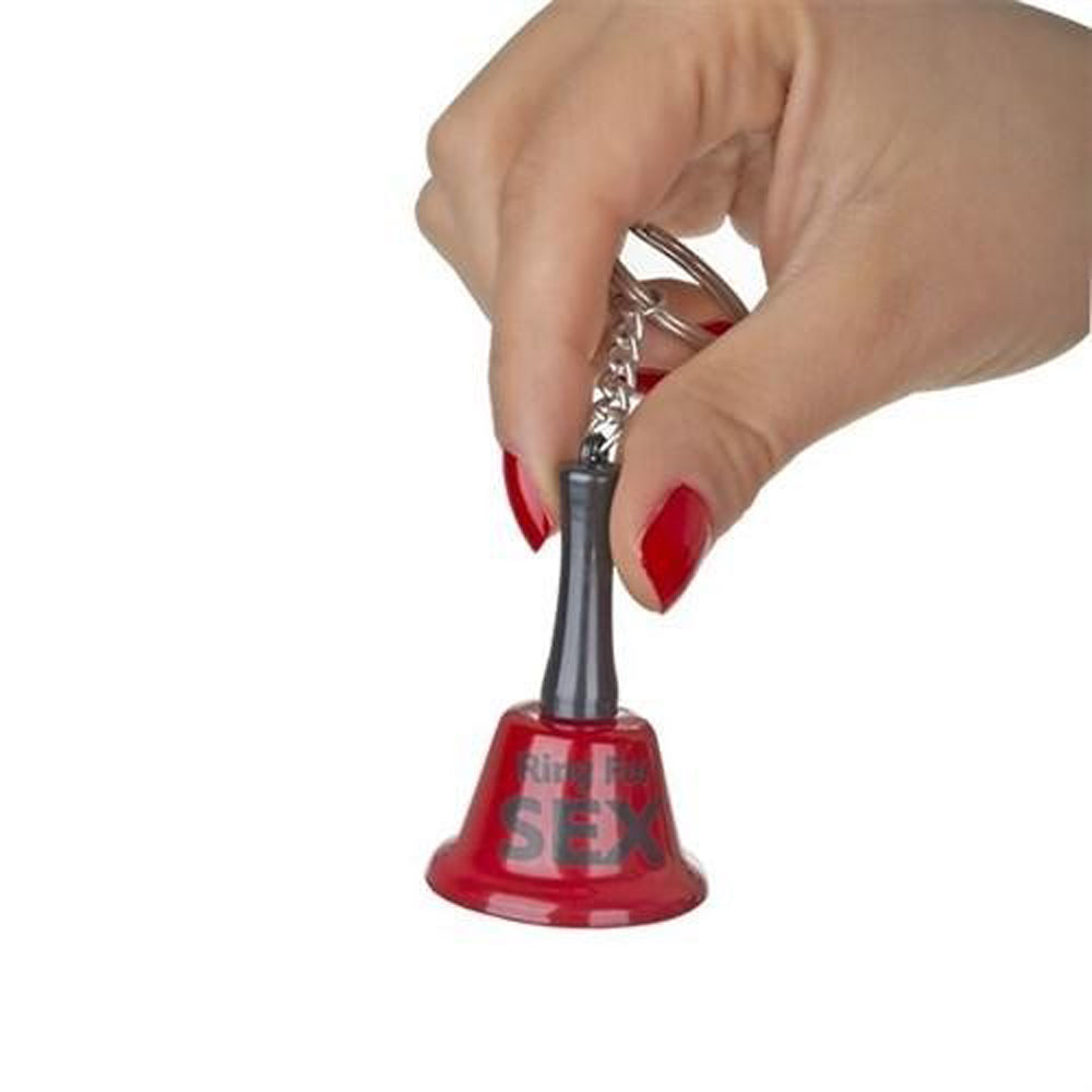 A hand holds a red novelty keychain bell that says "Ring For Sex".