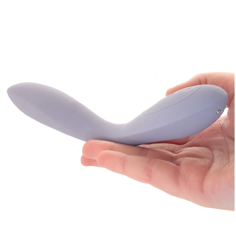 A purple silicone vibrator with a curved shape rests in a hand.