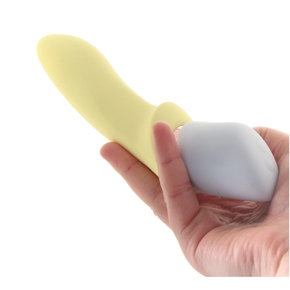 A hand holds a yellow vibrator with a grey attachment.