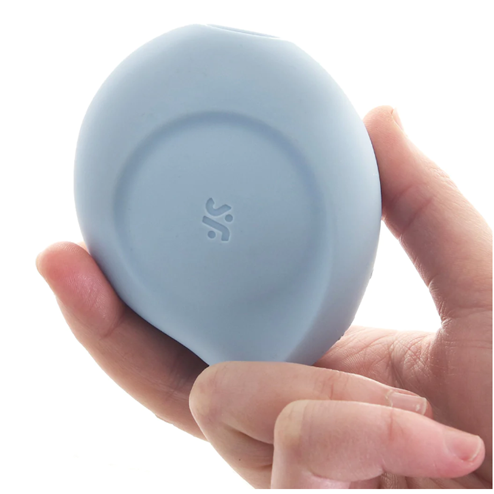 A light blue, egg-shaped clitoral toy with a subtle logo is held in a hand.