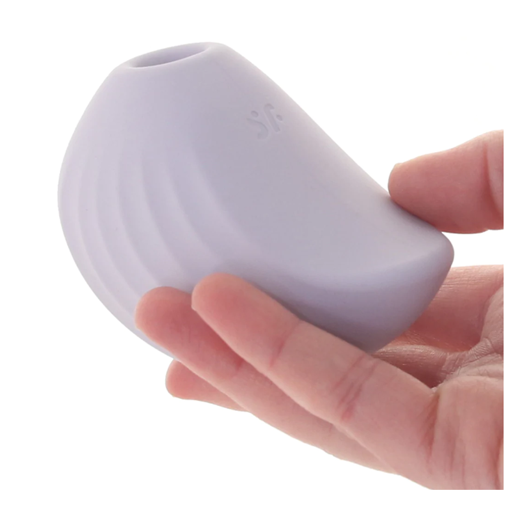 A light purple, shell-shaped clitoral vibrator with ribbed texture held in a hand.