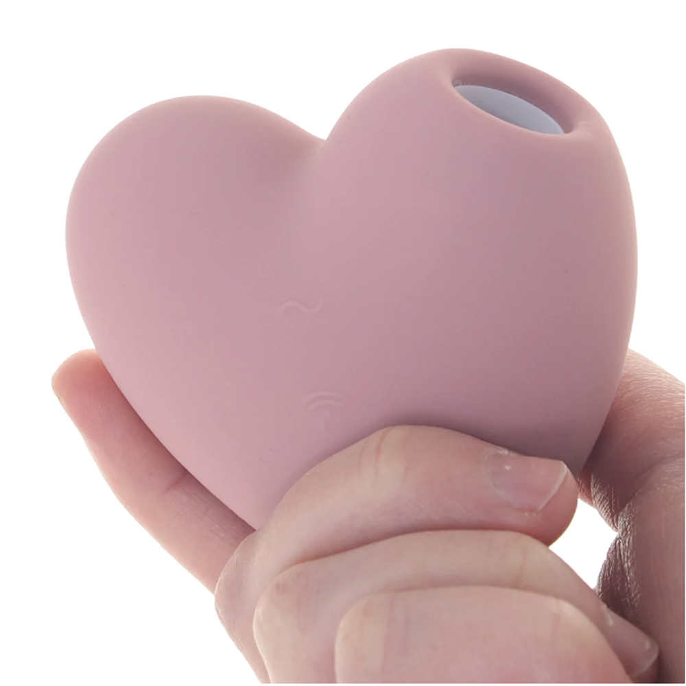 A pink heart-shaped vibrator held in a hand.