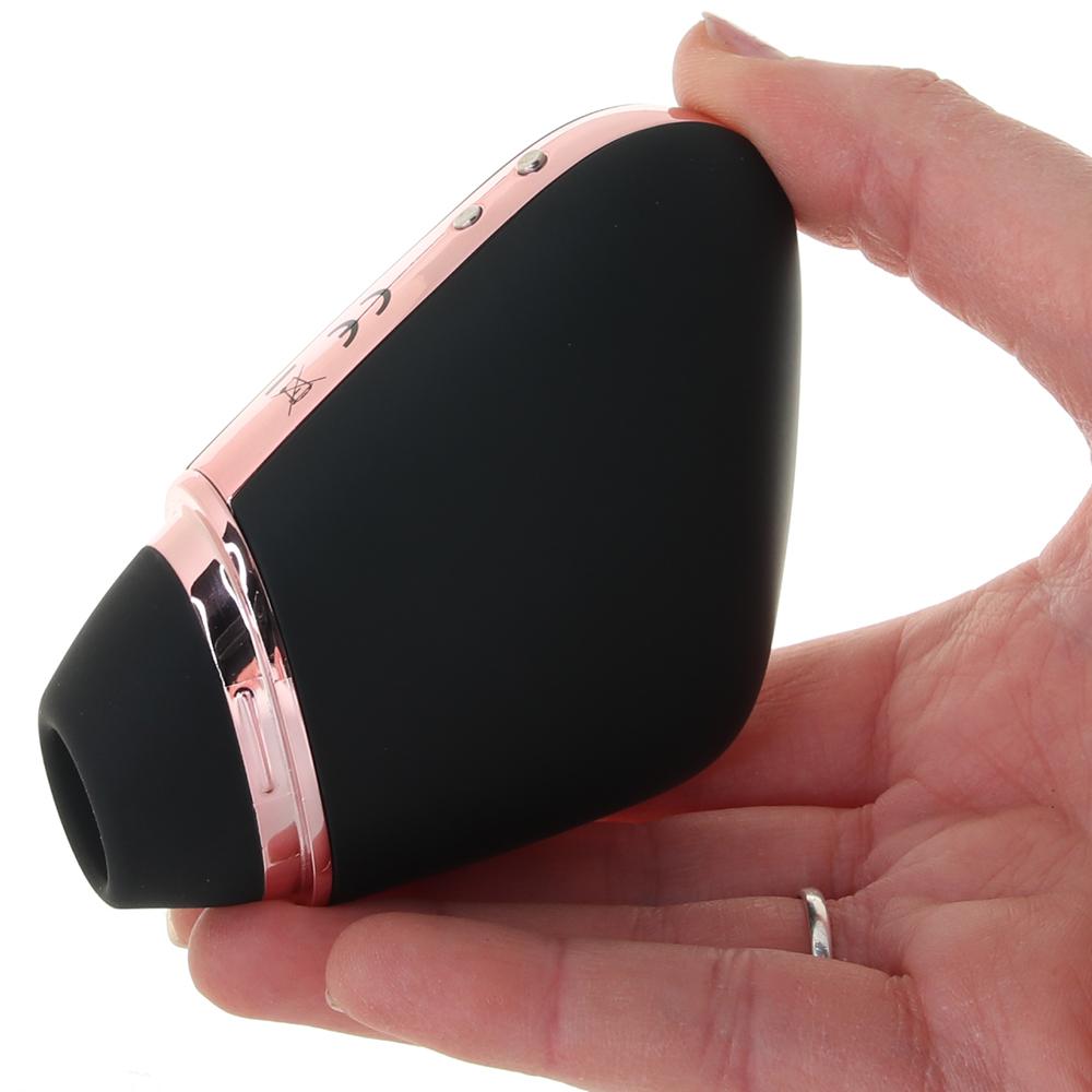 Black and rose gold app-controlled clitoral vibrator held in a hand.
