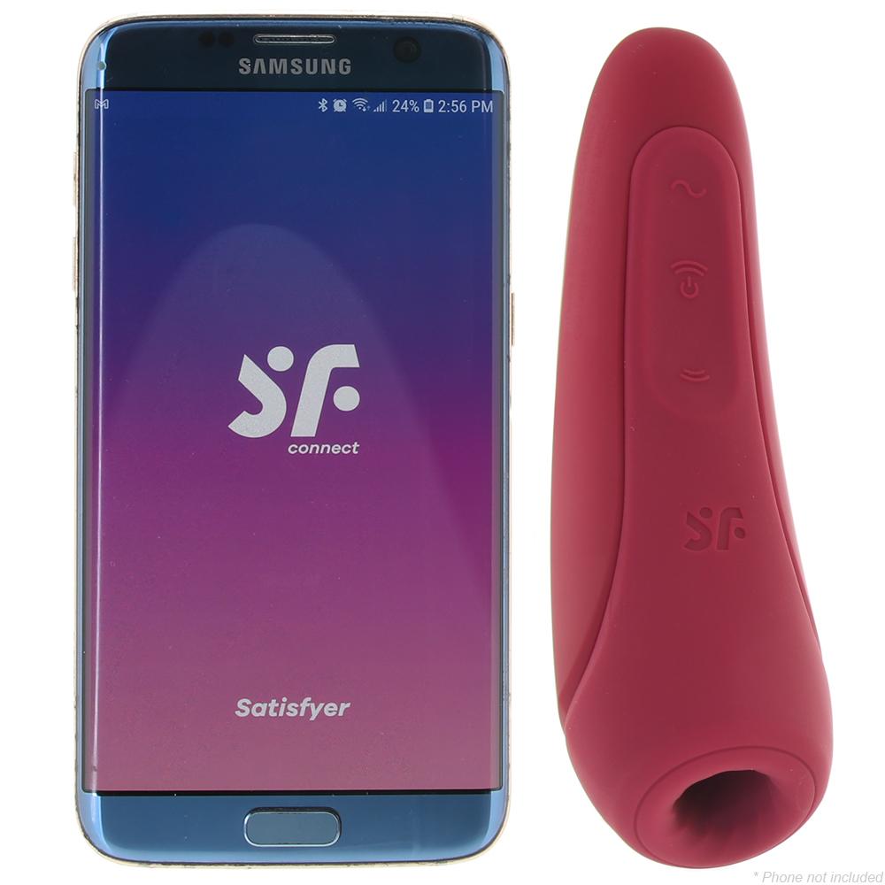 A pink air-pulse vibrator next to a smartphone displaying the Satisfyer app.