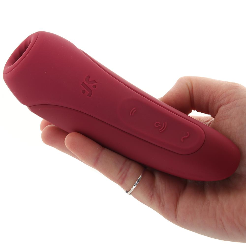 A red app-controlled vibrator with buttons and a logo held in a hand.