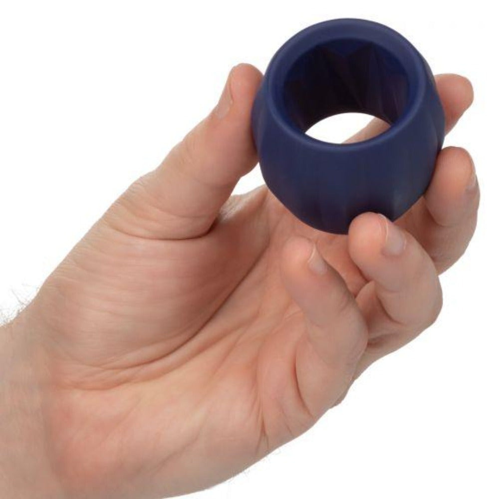 A dark blue, ribbed silicone cock ring held in a hand.