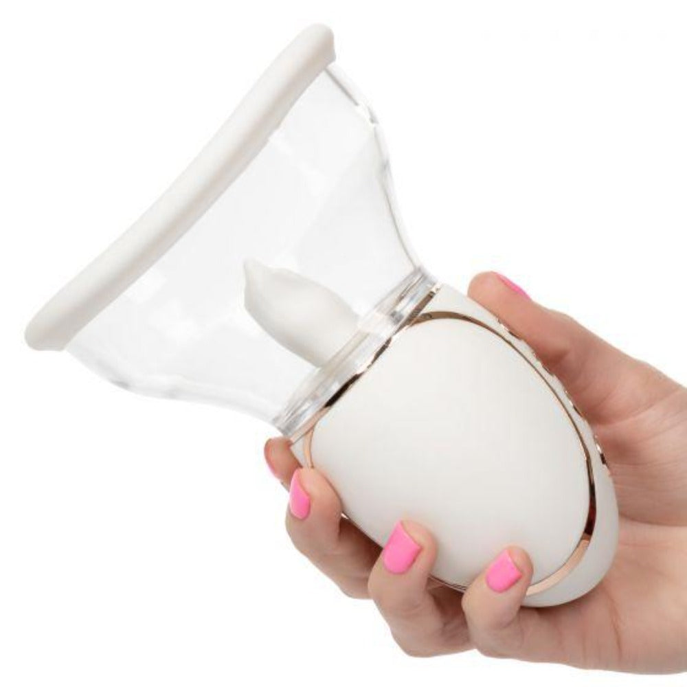 A white and rose gold vibrator with a clear suction cup held by a hand.