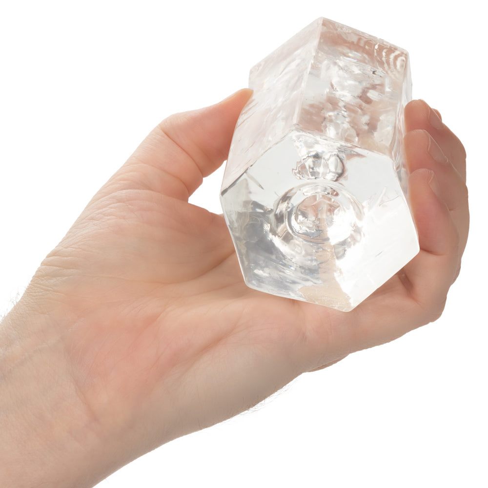 A hand holds a clear, faceted crystal masturbator.