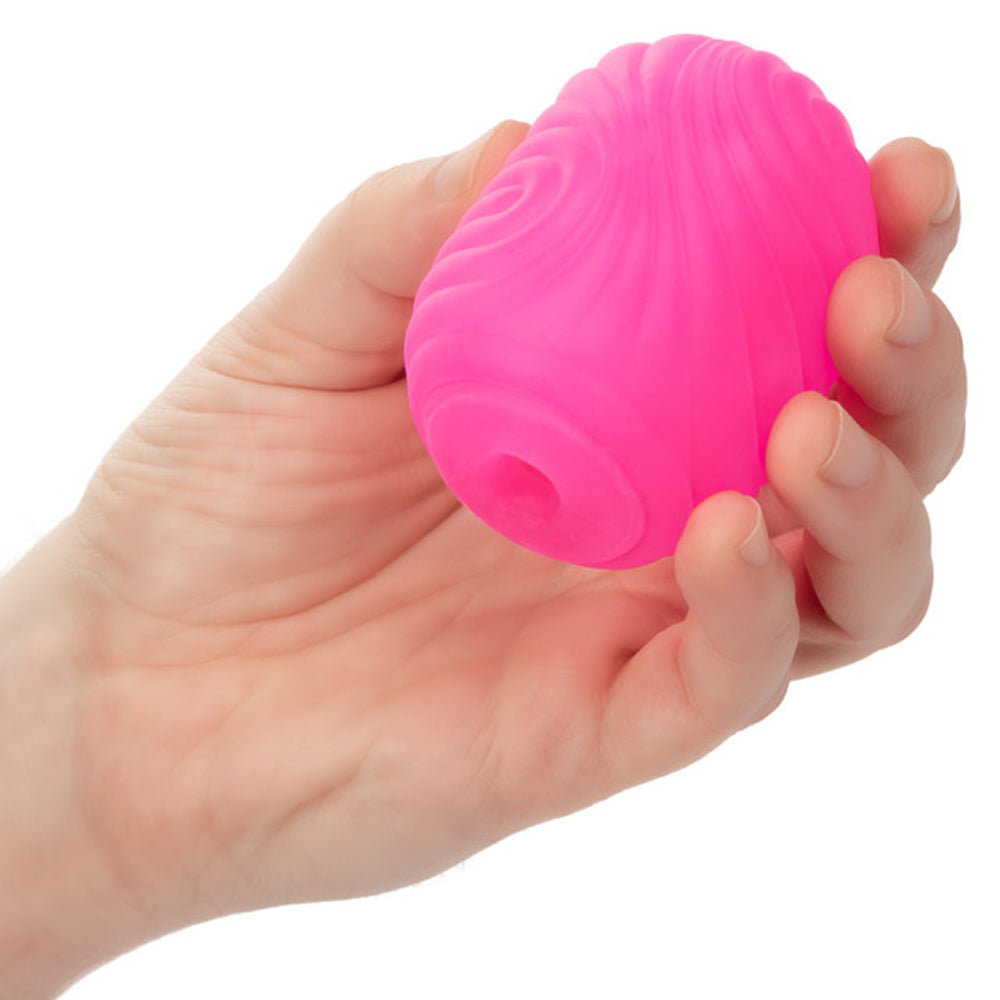 Pink textured reversible stroker with suction held in a hand.