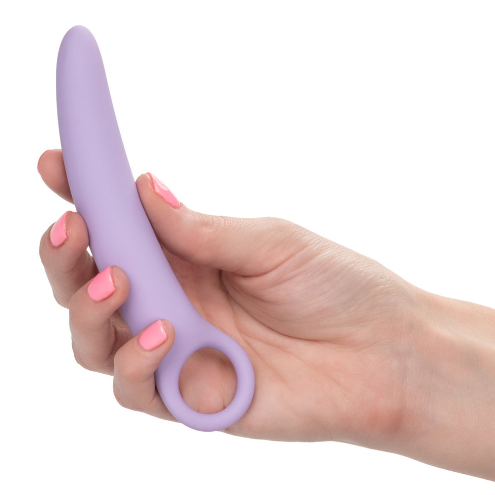A hand holds a purple silicone vaginal dilator with a finger loop.
