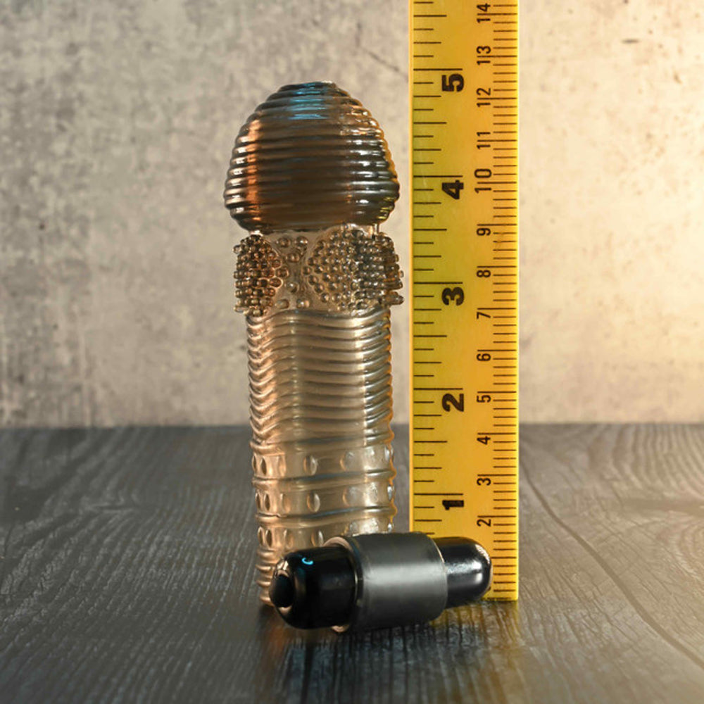 A vibrating penis sleeve set with a ruler for scale.