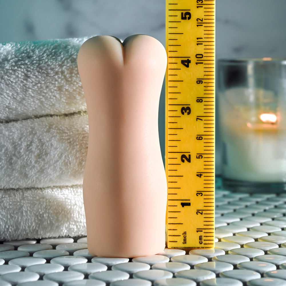 A beige textured stroker is shown next to a ruler measuring approximately 5 inches.