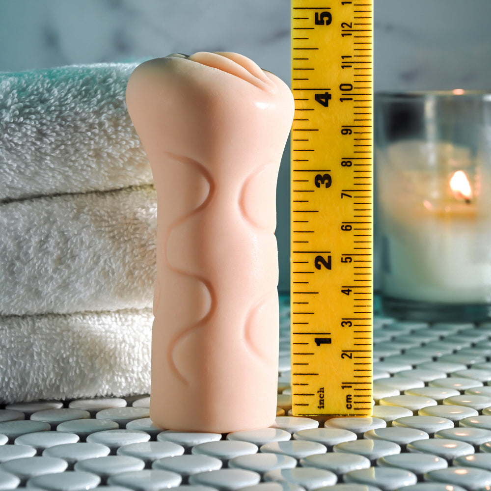 A pink textured stroker is shown next to a ruler.