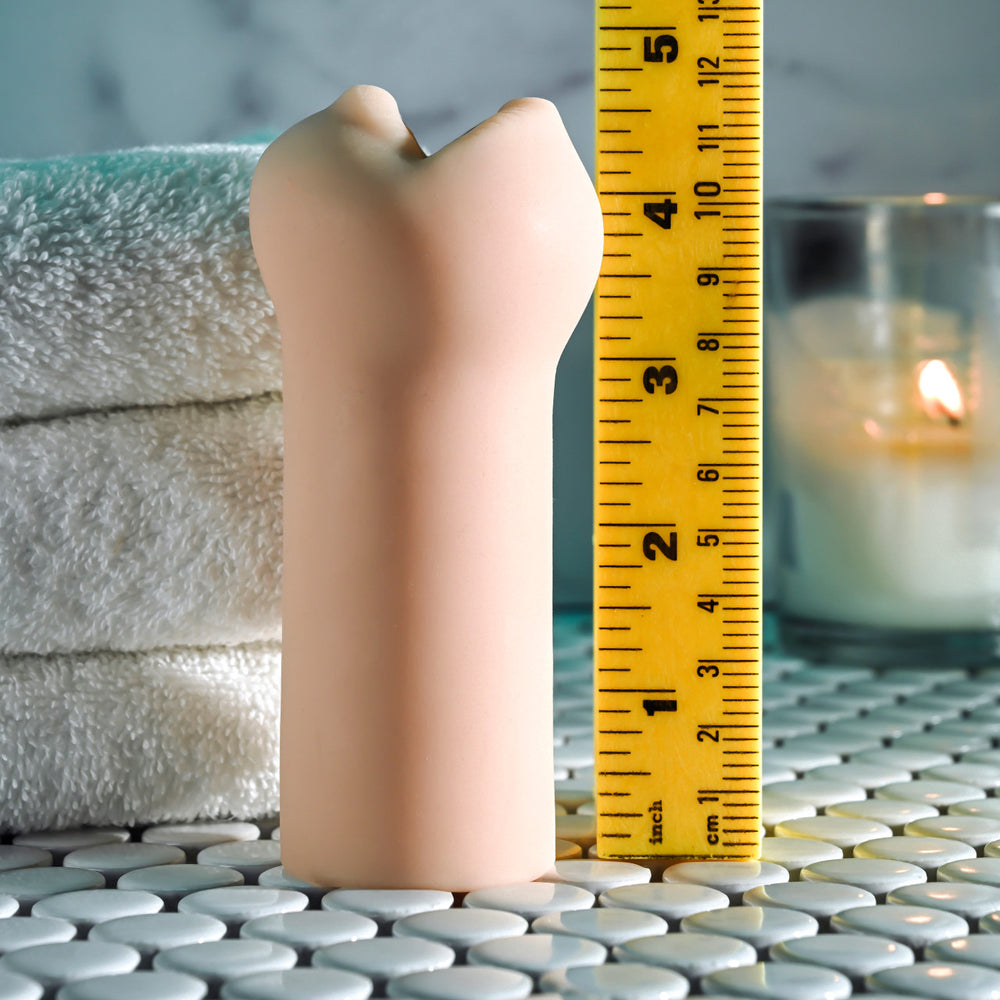 A flesh-toned textured stroker is shown next to a yellow ruler.