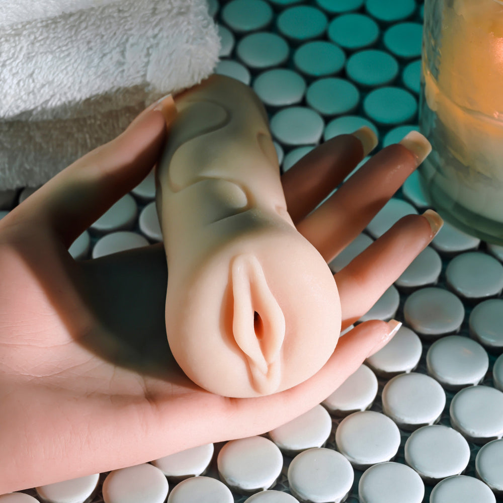 A hand holds a textured stroker with a realistic appearance.