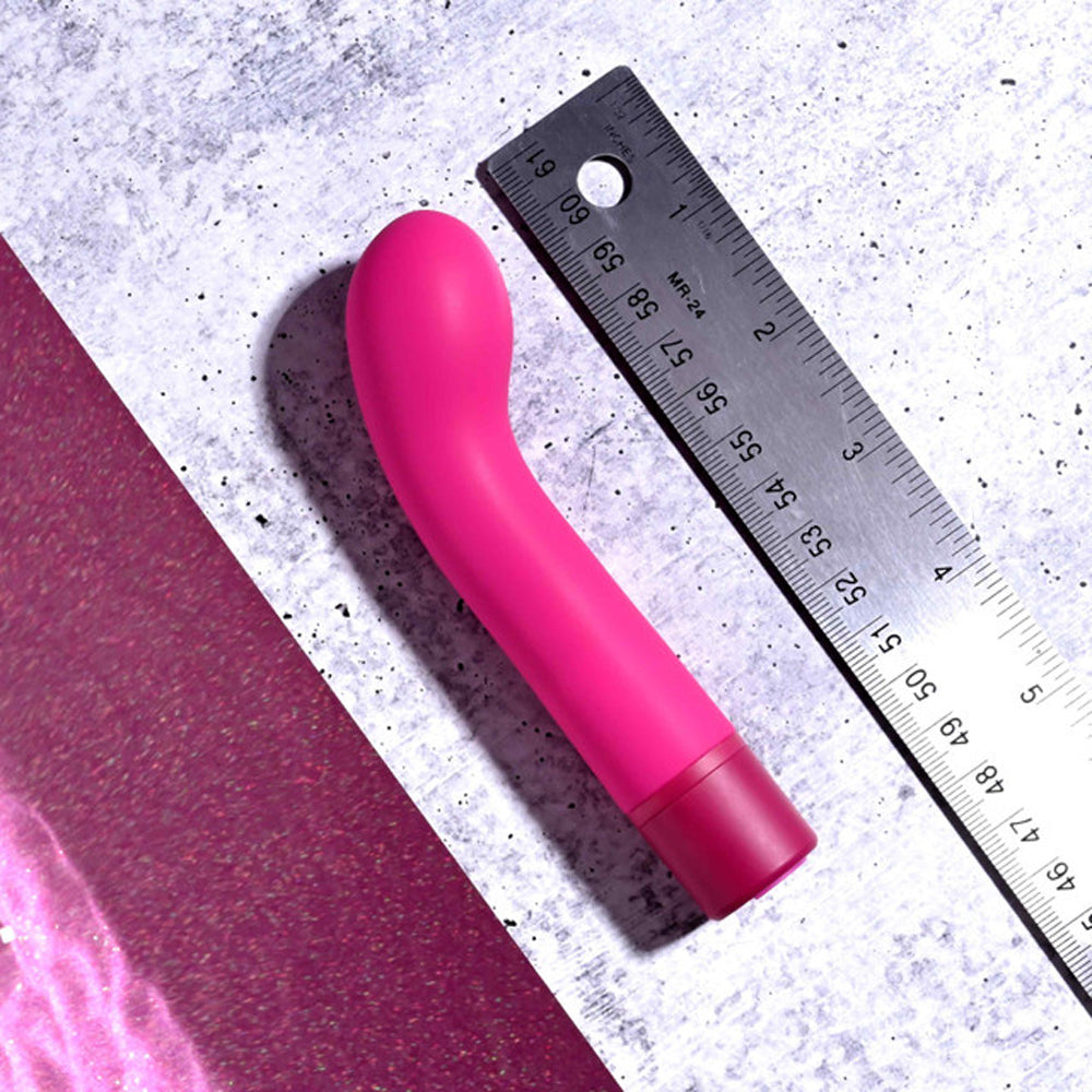 A pink G-spot vibrator with a curved head and a dark pink base, next to a ruler.