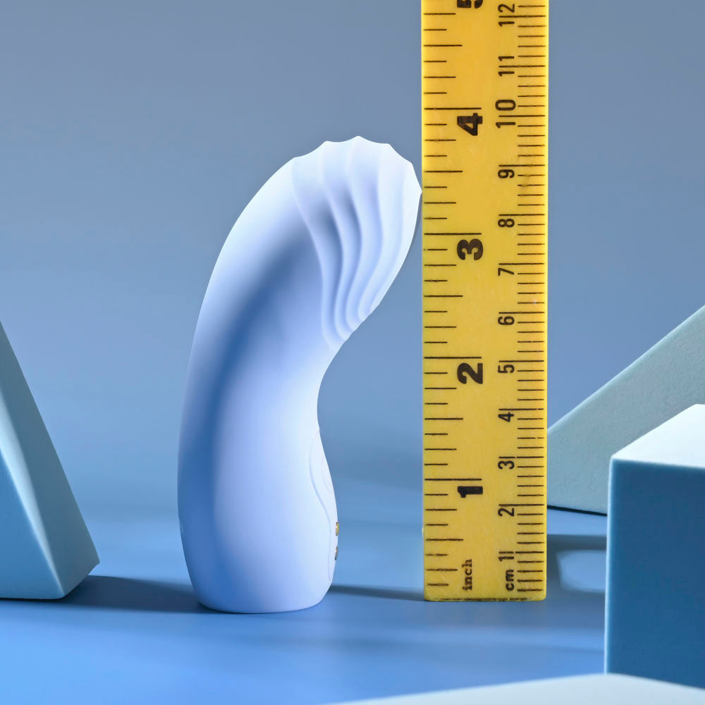 A white, curved silicone finger vibrator is measured against a yellow ruler.